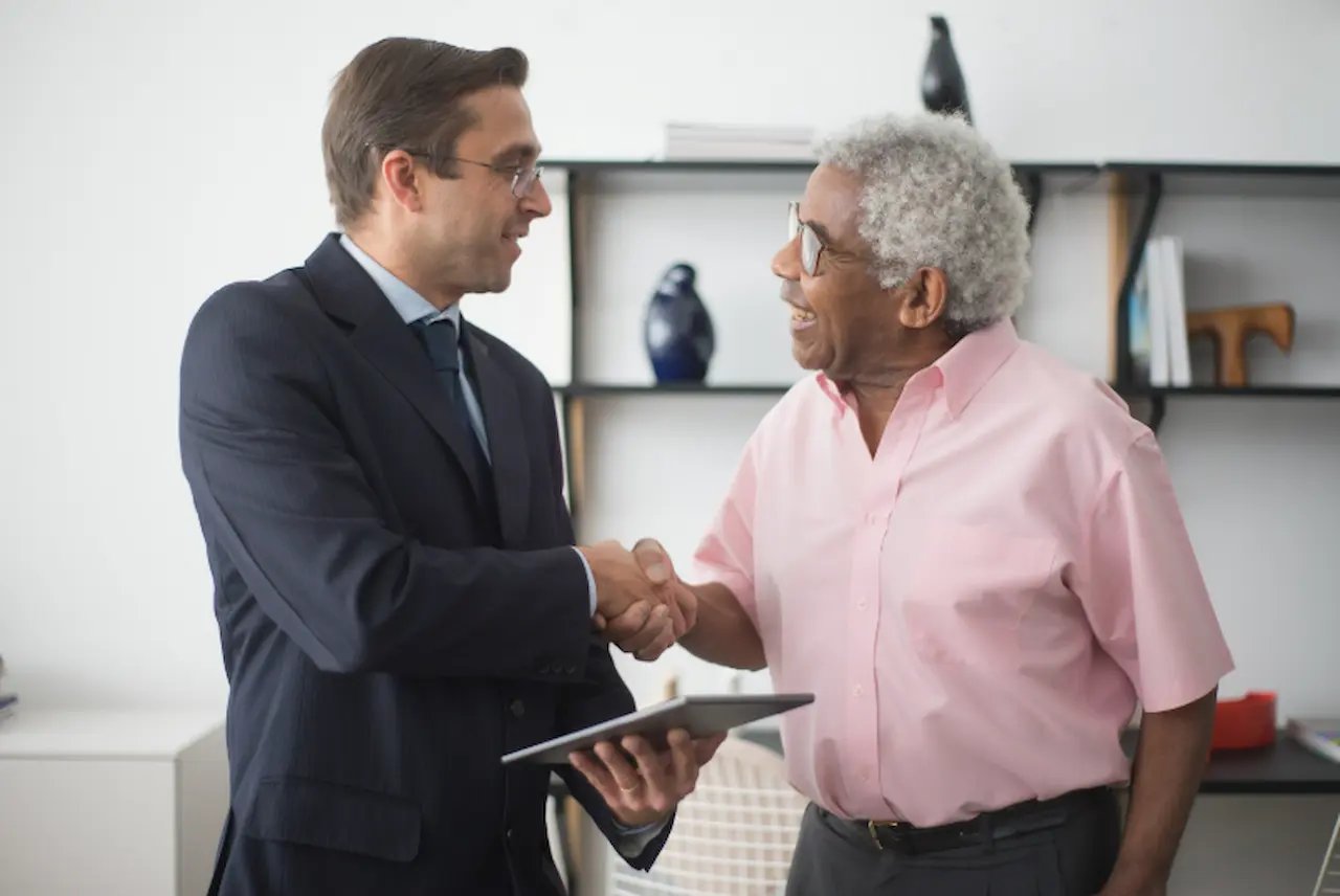 Elderly man smiling while being assisted by a young woman